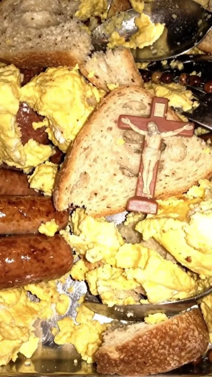 Un crucifijo hundido en huevos revueltos, salchichas y pan.