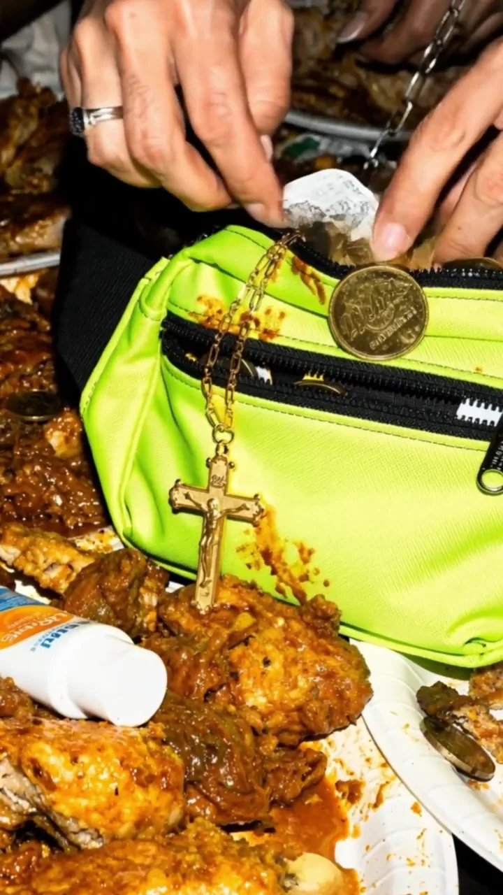 Unas manos con anillos sacan una moneda de una riñonera junto a una cruz y comida.